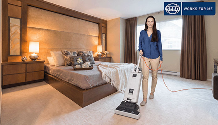 Reinigungskraft reinigt ein Hotelzimmer mit dem Bürststaubsauger SEBO AUTOMATIC XP 20.