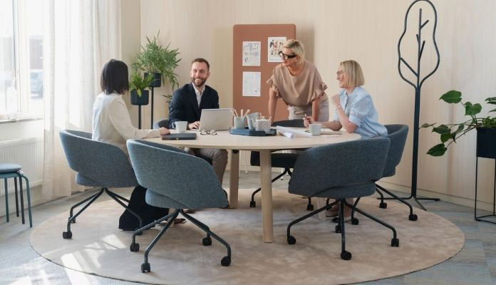 Vier Personen besprechen gemeinsam Unterlagen an einem Tisch in einem Büro.